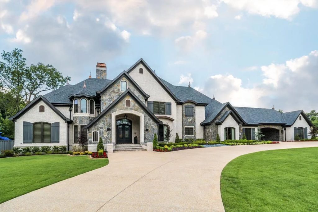 Elegant European-inspired home with stone and brick exterior, steep gables, and arched entryway