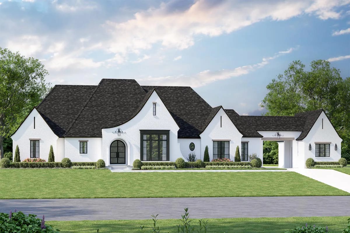 Elegant white brick home with steep gabled roof, arched entry, and porte-cochère in a manicured landscape.