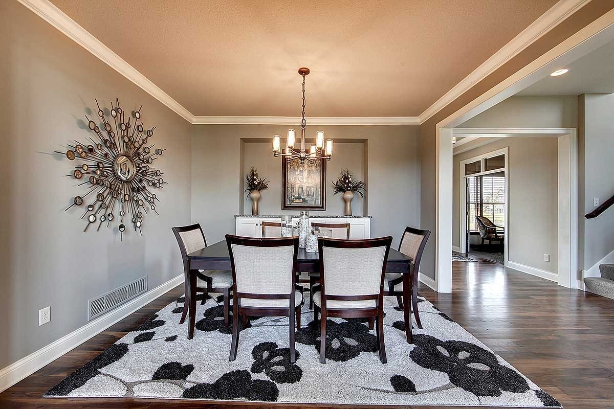 Formal dining room with dark wood table, modern chandelier, and bold patterned rug