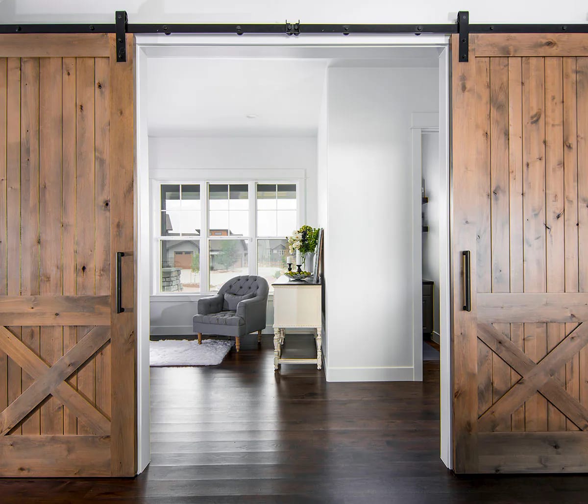 Interior view with rustic barn doors and bright sitting area beyond