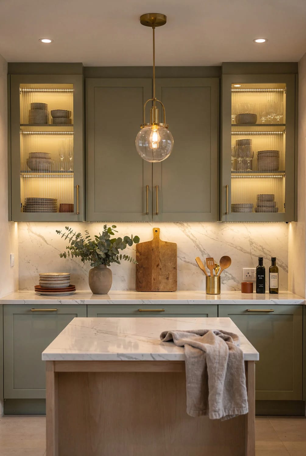 Kitchen Remodel Inspiration With Layered Lighting Kitchen remodel inspiration showing a compact kitchen with illuminated glass-front cabinets, under-cabinet lighting, two recessed ceiling lights, and a central pendant above the island
