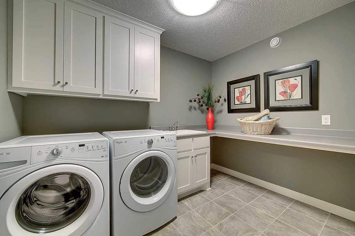 Laundry room with white cabinets, washer and dryer, gray countertops, and tile floor
