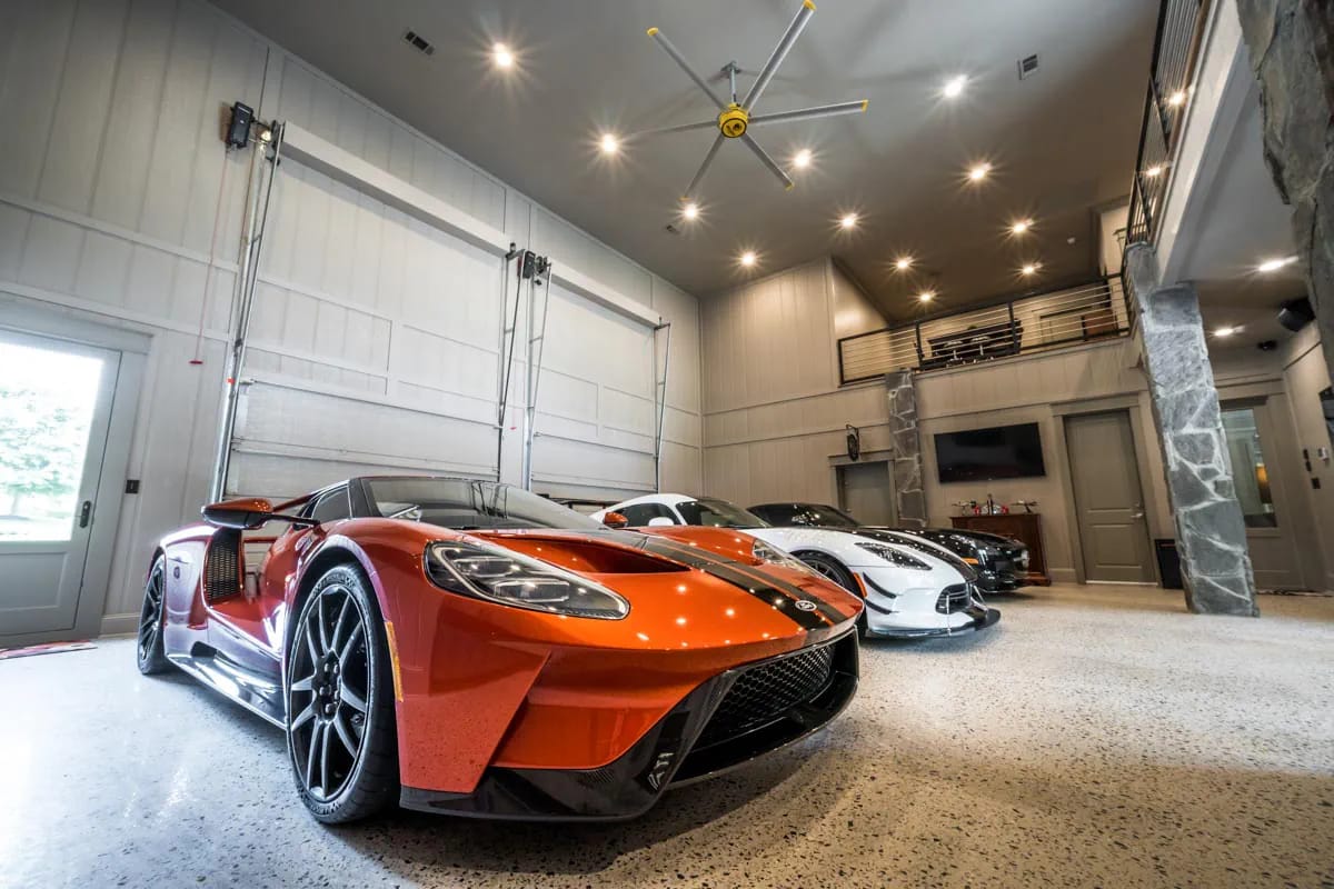 Luxury garage interior with high ceiling, polished floor, mezzanine, and sports cars
