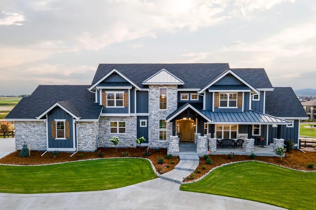 Modern farmhouse exterior with stone and blue siding, gabled roof, and covered porch