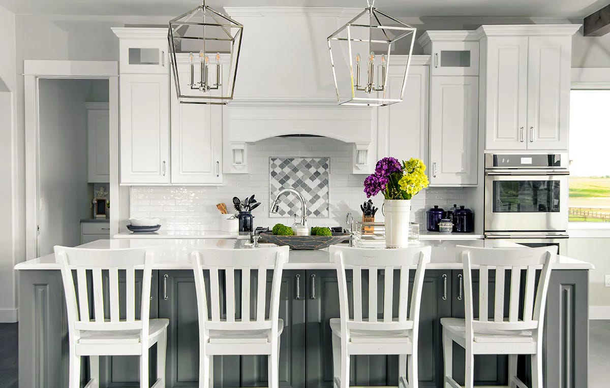 Modern kitchen with white cabinetry, gray island, and geometric pendant lights