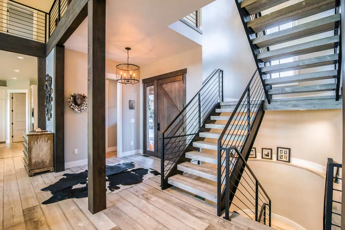 Modern rustic entry hall with open wood and metal staircase and barn-style front door
