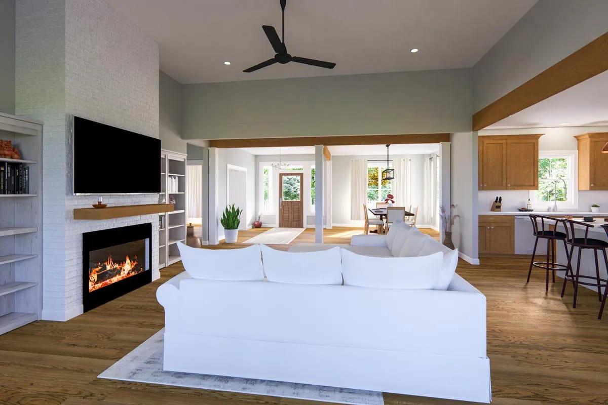 Open-plan living room with white brick fireplace, wood beams, kitchen, dining area, and white sofa