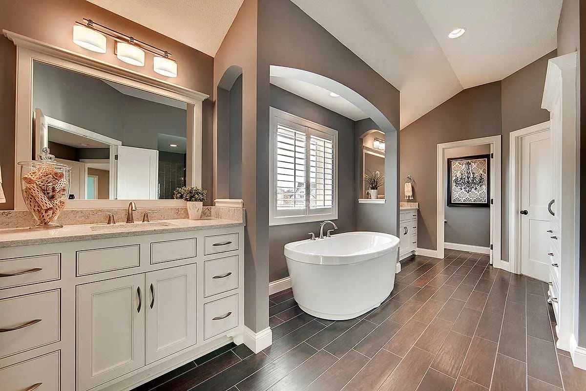 Primary bathroom with freestanding tub, double vanities, and dark wood-look tile floor