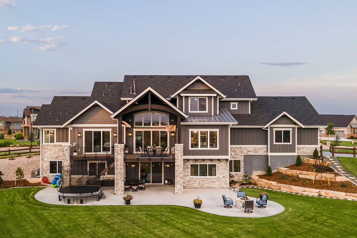 Rear exterior rendering of a large modern craftsman-style home with stone and siding finishes.