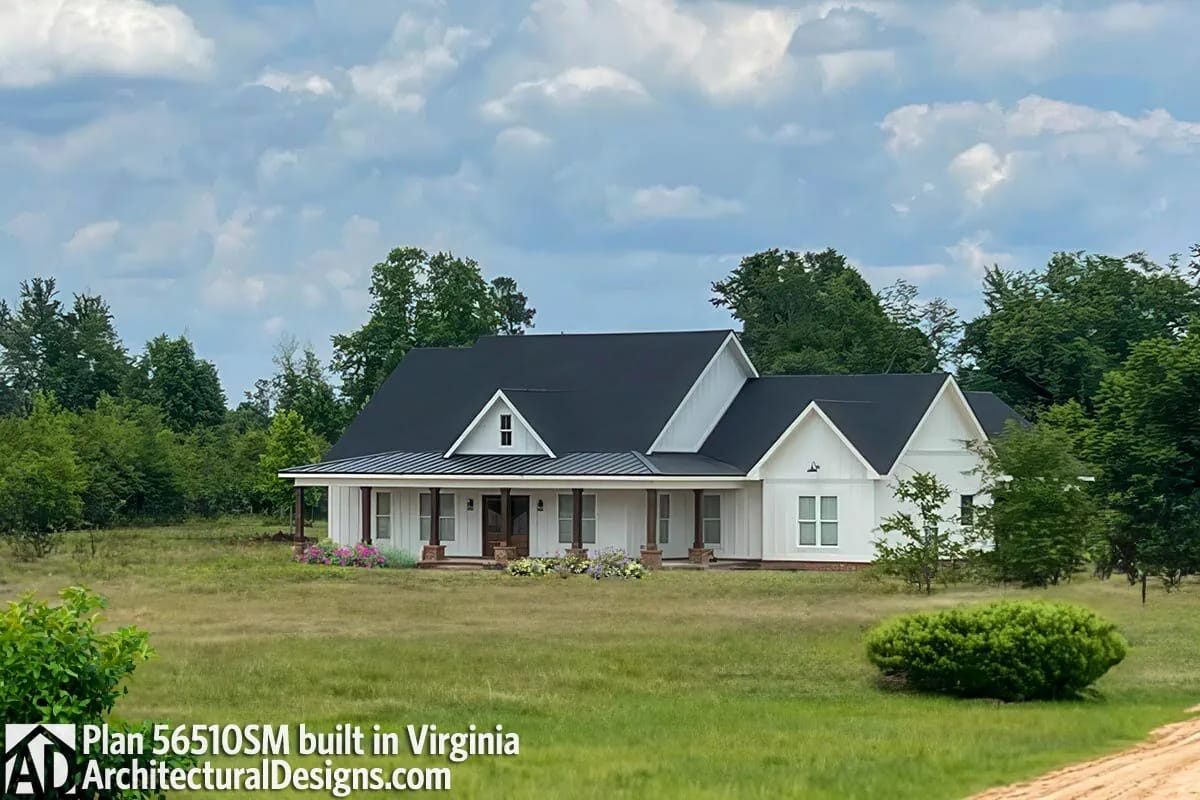 Single-story white farmhouse with dark gabled roofs and a long covered front porch Single-story white farmhouse with dark gabled roofs and a long covered front porch