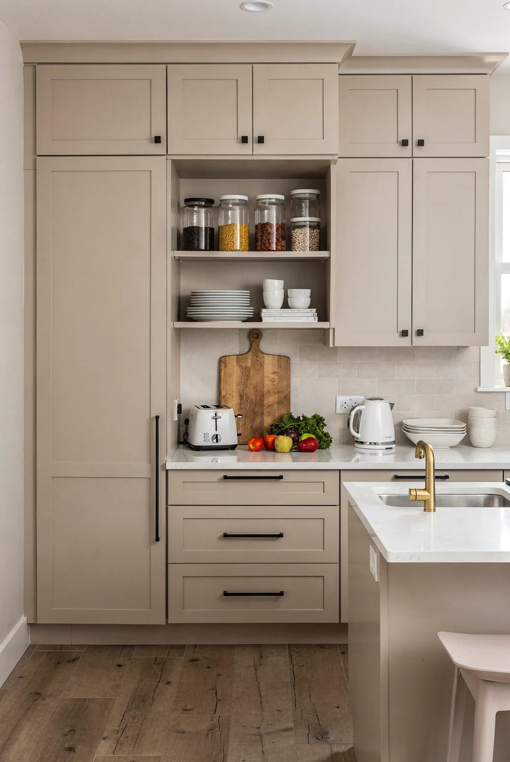 Small Kitchen Remodel With Full Cabinet Wall Small kitchen with a full wall of light-colored cabinets, open shelves holding jars and dishes, a countertop with appliances and produce, and a sink island with a brass faucet.
