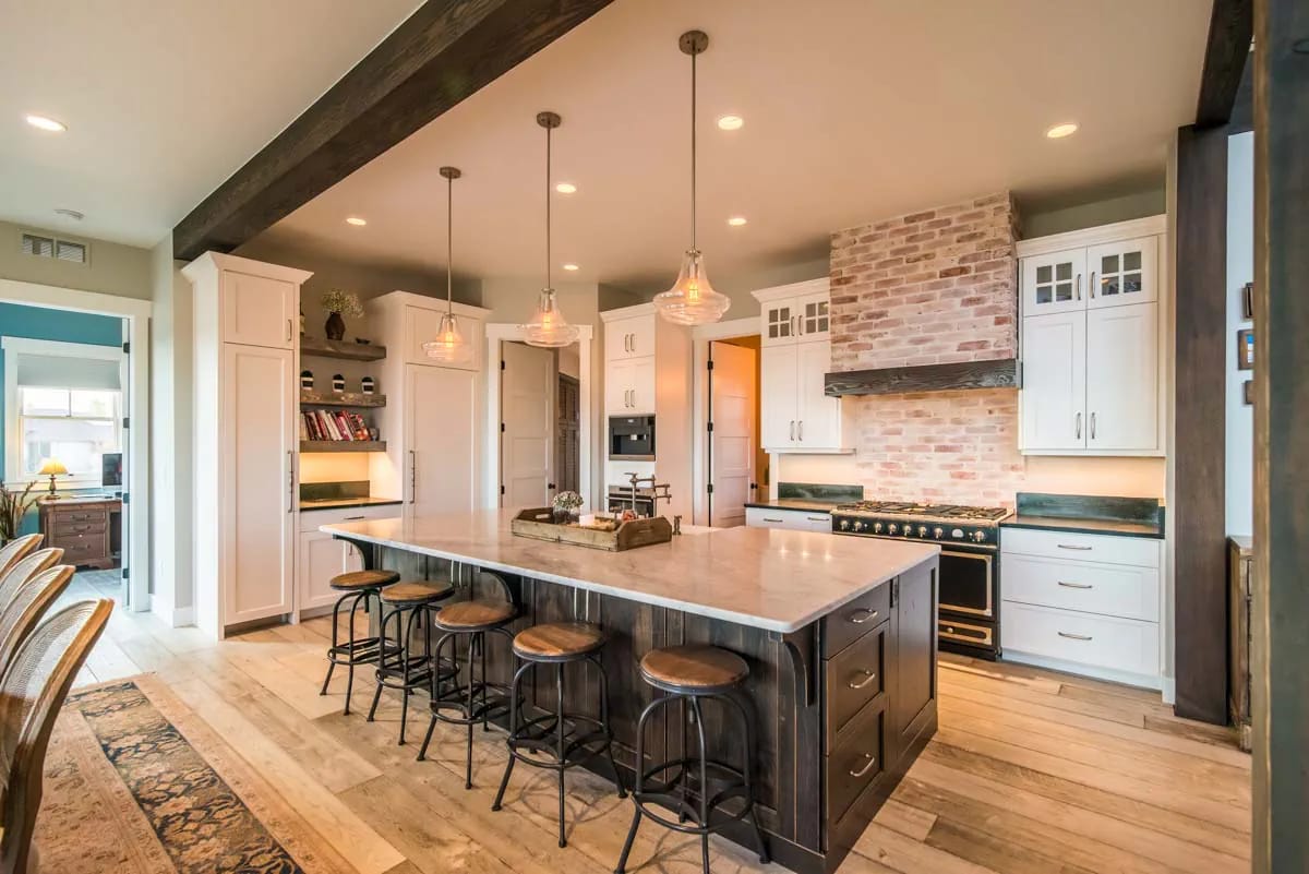 Spacious kitchen with large island, exposed brick backsplash, and white shaker cabinets