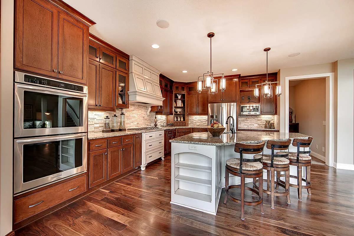 Spacious kitchen with wood cabinets, granite island, pendant lights, and stainless steel appliances