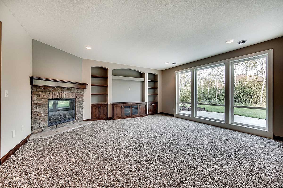 Spacious living room with stone fireplace, built-in cabinetry, and large windows overlooking the yard.