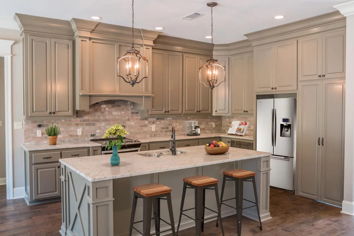 Traditional taupe-gray kitchen with brick backsplash, large island, pendant lights, and wood flooring