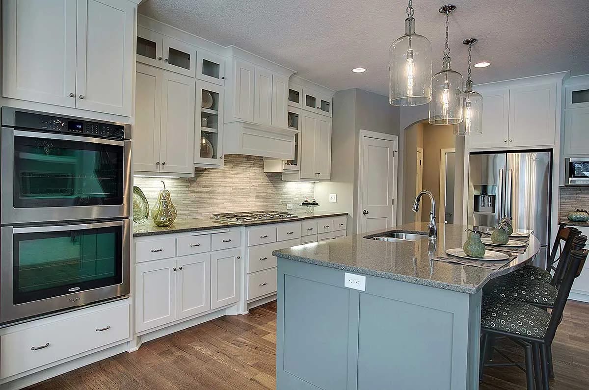 Transitional kitchen with white cabinetry, gray island, double ovens, and pendant lighting