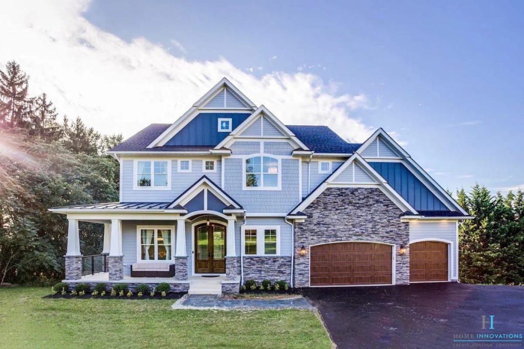 Two-story home with stone and siding facade, covered front porch, and three-car garage