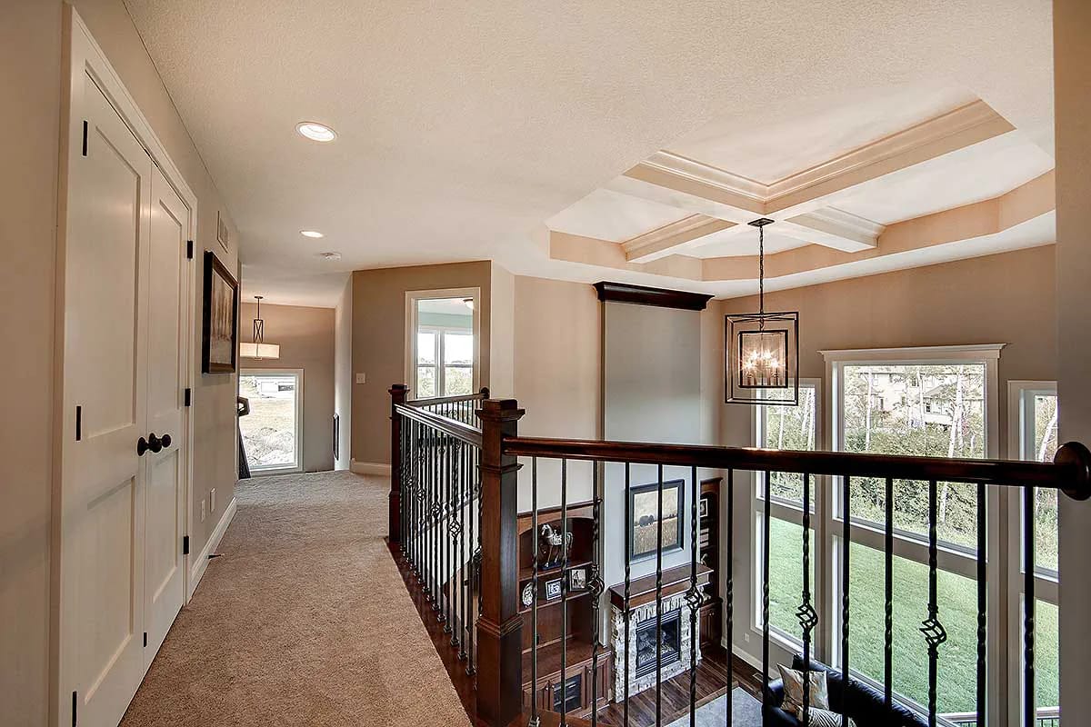 Upstairs gallery with dark wood railing overlooking double-height living room and large windows