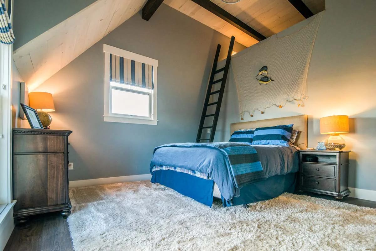 Vaulted ceiling bedroom with blue bedding, wood beams, and loft ladder