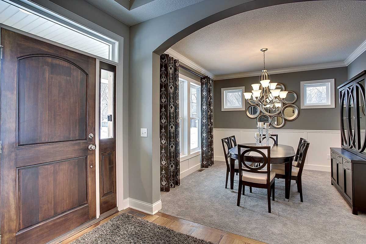 View from entry into elegant dining room with arched opening, chandelier, and dark wood finishes