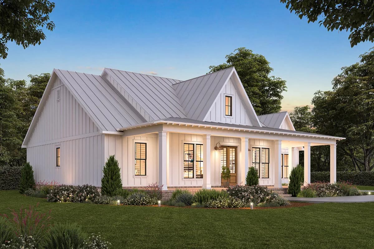 White board-and-batten cottage with metal gables and a covered porch surrounded by landscaped beds White board-and-batten cottage with metal gables and a covered porch surrounded by landscaped beds