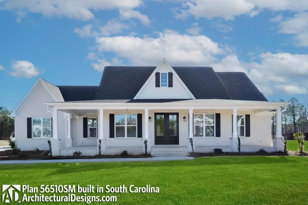 White brick home with black shutters, intersecting gables, and a full-width covered front porch White brick home with black shutters, intersecting gables, and a full-width covered front porch