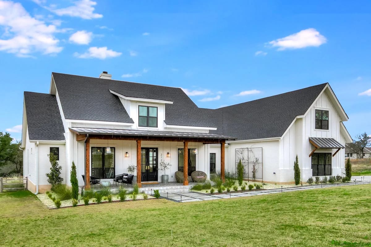 4-Bedroom Modern Farmhouse House Plan with a Bonus Room and Full Bath Over the Garage (2,686 Sq. Ft. Floor Plan) 1 White gabled home with dark roof, covered wood-post porch, black windows, and landscaped lawn