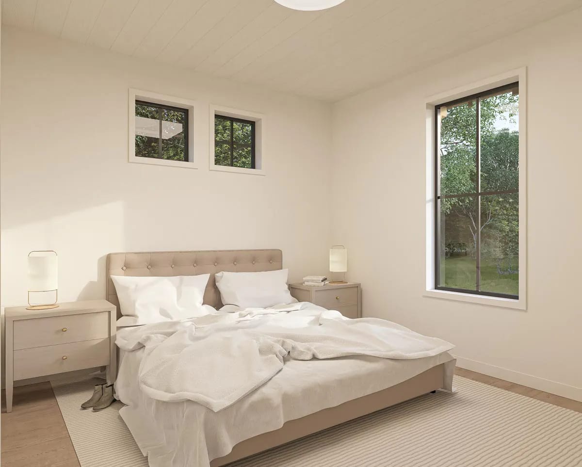 Bright neutral bedroom with upholstered bed, wood nightstands, large windows, and a leafy outdoor view Bright neutral bedroom with upholstered bed, wood nightstands, large windows, and a leafy outdoor view