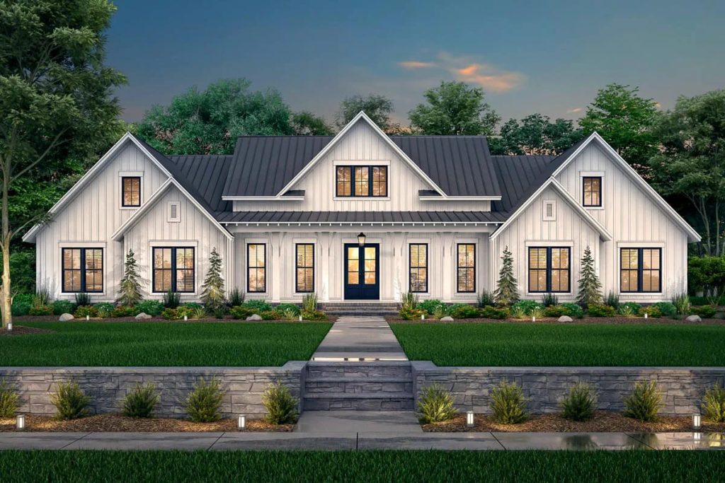 Lovely Harbor 27 Symmetrical white farmhouse exterior with dark metal roofs, central porch, stone wall, and landscaped walkway