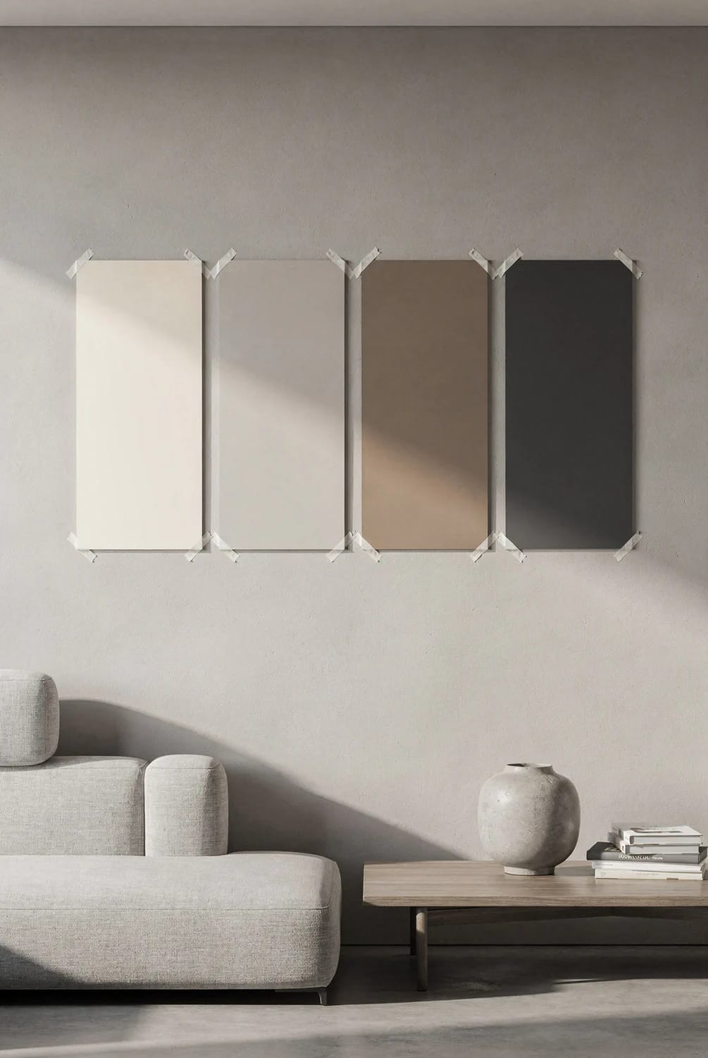 Test Paint Colors Around The Room Four paint color sample boards in light, neutral, taupe, and dark shades are taped to a living room wall above a sofa and coffee table, illustrating how to test paint colors before buying